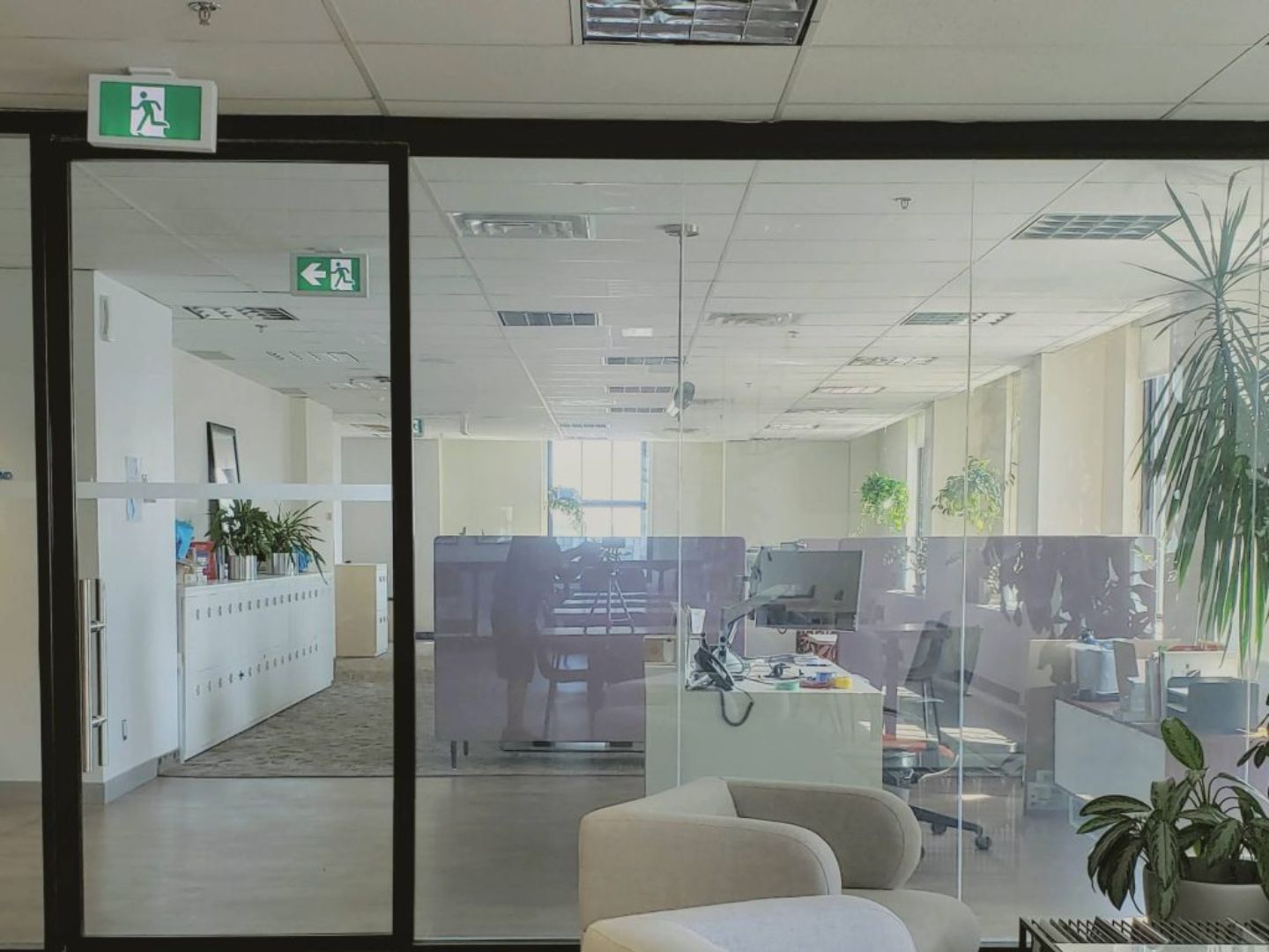 Glass-walled modern office with desks and plants