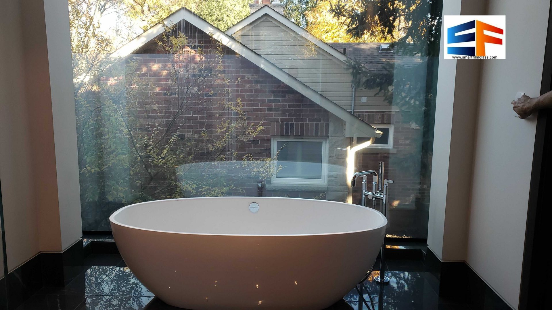 Freestanding bathtub by large window overlooking house
